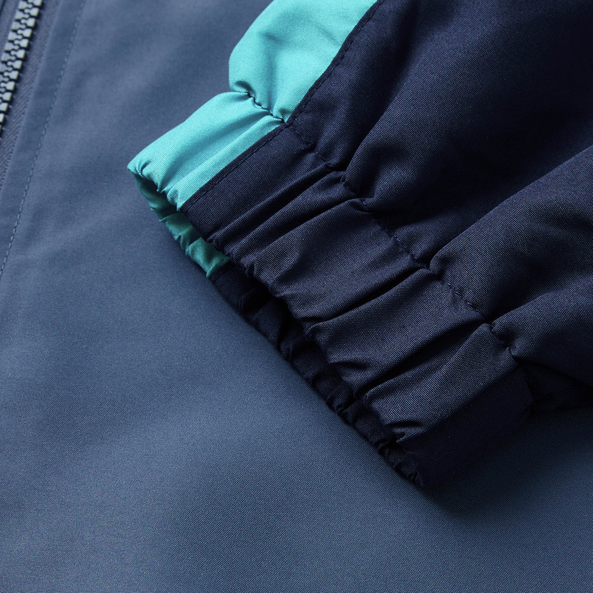 Close-up of the cuff and sleeve of the Ireland 26 Legends 1/4 Zip Jacket by Canterbury in navy blue with a teal stripe, highlighting the elastic material and part of the zipper.