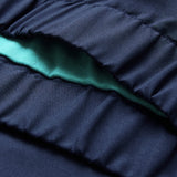 Close-up of gathered navy blue fabric from the Canterbury Ireland 26 Legends 1/4 Zip Jacket, with a visible layer of light teal fabric underneath.