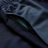 Close-up of a dark-colored garment with an open zipper pocket, revealing green fabric inside and an elastic waistband at the top—features that showcase the quality construction typical of Canterbury’s Ireland 26 Legends 32″ Trackpant.