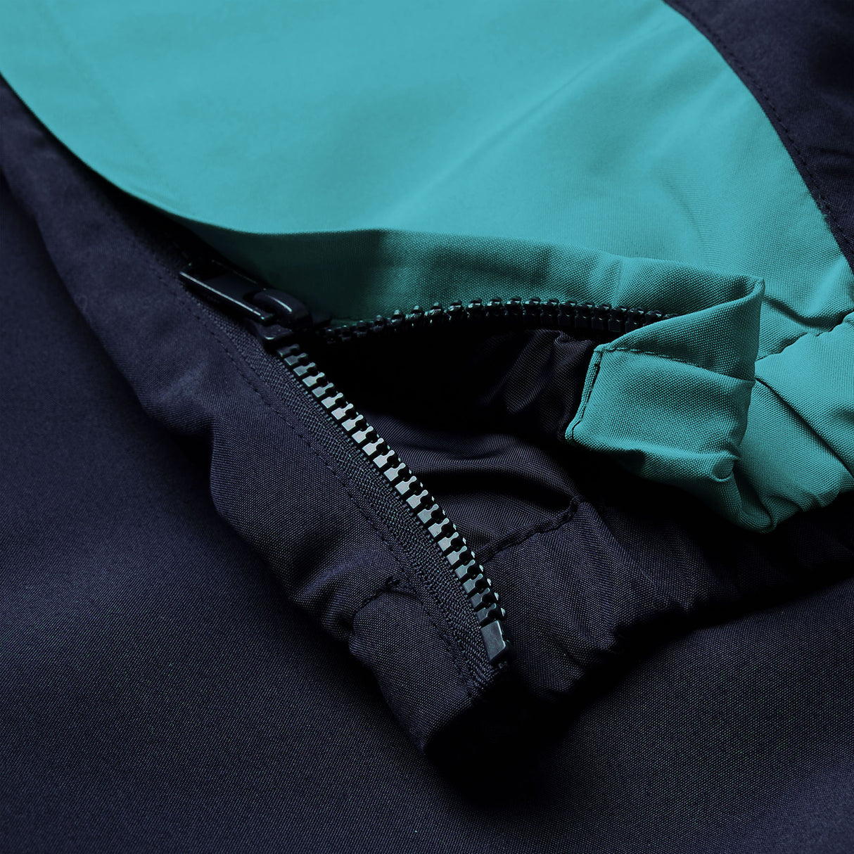 Close-up of a black and teal fabric jacket, featuring a partially open zipper and visible stitching details, reminiscent of the high-quality design found in the Canterbury Ireland 26 Legends 32″ Trackpant.