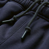 Close-up of dark blue sweatpants featuring an elastic waistband with two drawstrings tied in knots and plastic aglets, reminiscent of the secure fit found in the Canterbury Ireland 26 Legends 7″ Shorts.
