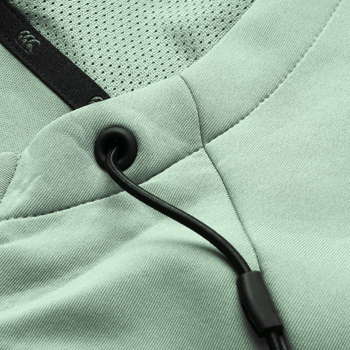 Close-up of the Canterbury Everest Zip Thru Hoodie in light green, featuring black drawstrings with metal grommets, mesh lining, and detailed stitching—a Canterbury performance hoodie blending comfort and style.