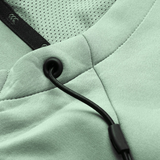 Close-up of the Canterbury Everest Zip Thru Hoodie in light green, featuring black drawstrings with metal grommets, mesh lining, and detailed stitching—a Canterbury performance hoodie blending comfort and style.