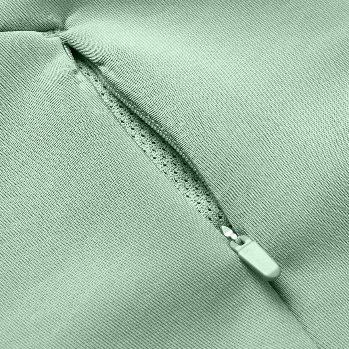 Close-up of a Canterbury Everest Zip Thru Hoodie pocket in light green by Canterbury, showing a partially open zipper and the inner lining.