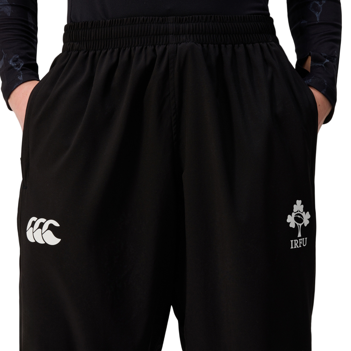 Woman wearing Canterbury Women's Ireland 25/26 Training Pant, with the Canterbury logo on the left leg and IRFU shamrock crest on the right, hands in pockets.