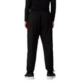 A person faces away, wearing Canterbury Women's Ireland 25/26 Training Pant with an athletic tapered fit, a long-sleeve black top, and black sneakers with white soles against a white background.