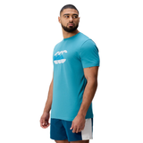 A man wearing a Canterbury FUN. T-SHIRT AM with a white graphic and blue shorts featuring a white side panel stands looking to his left.