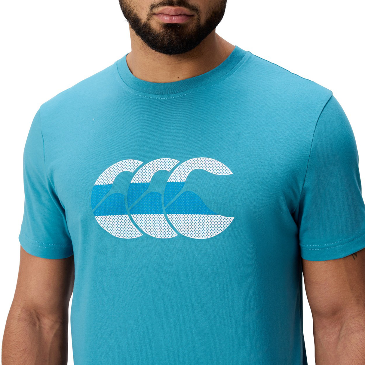A man wears the Canterbury FUN. T-SHIRT AM, featuring a playful graphic of three overlapping white and blue waves on the chest.
