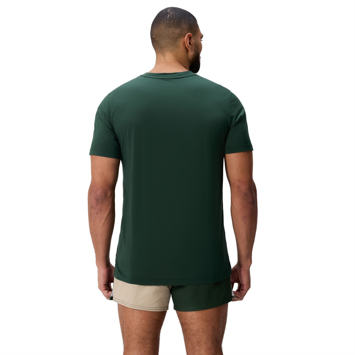 A man faces away wearing a Canterbury FUN. T-SHIRT AM in dark green and beige shorts with green trim, set against a plain white background.