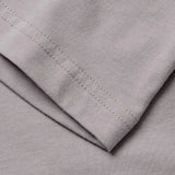 Close-up of a light gray fabric with visible stitching along the edge, displaying the texture and seam details characteristic of athletic casual wear, such as the Canterbury Fundamentals T-shirt by Canterbury.