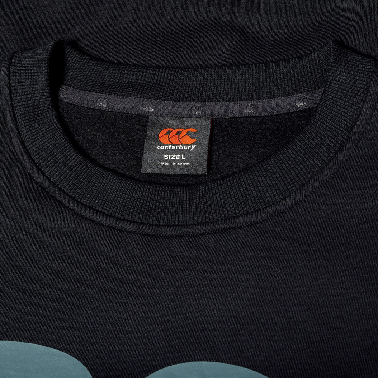 Close-up of a black Canterbury shirt collar with a visible label showing size L and made in China—ideal for daily wear or pairing with your Canterbury EVERYDAY GFX CREW SWEATER.