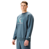 A man in a blue Canterbury EVERYDAY GFX CREW SWEATER and matching sweatpants stands facing forward against a white background, highlighting this comfortable Canterbury style for daily wear.