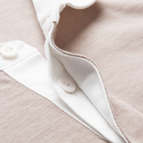 Close-up of the Stripe Rugby by Canterbury: beige fabric with white placket and two white buttons, showcasing the durable cotton blend and fine stitching.