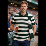 At the stadium, a man holds a pint of beer and sports a Canterbury Yarn Stripe Polo by Canterbury, paired with a matching scarf for classic rugby style.