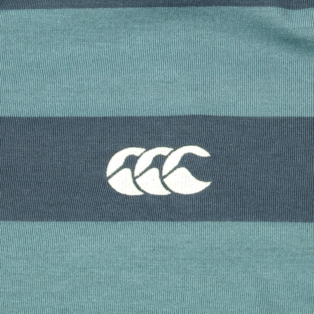 Close-up of the Canterbury Yarn Stripe Polo by Canterbury, displaying horizontal green and dark blue stripes with a white CCC logo at the center, highlighting its classic rugby style.