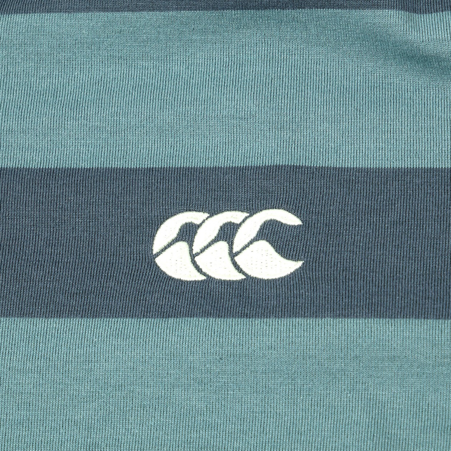 Close-up of the Canterbury Yarn Stripe Polo by Canterbury, displaying horizontal green and dark blue stripes with a white CCC logo at the center, highlighting its classic rugby style.