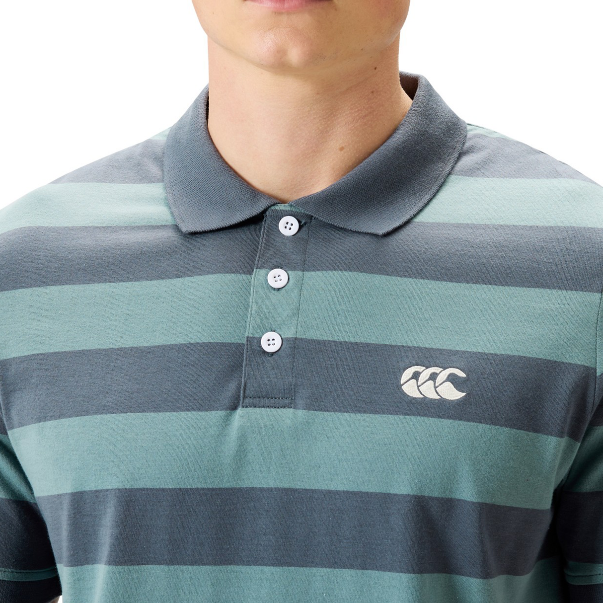 A person wearing the Canterbury Yarn Stripe Polo by Canterbury, featuring green and gray stripes, a collared neckline with three buttons, and a white chest logo for a classic rugby look.