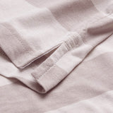 Close-up view of the side seam of the Canterbury Yarn Stripe Polo by Canterbury in a light color, highlighting its classic rugby-inspired design with a small side slit and prominent stitching details.