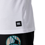 Close-up of a person in a white Canterbury Uglies Logo T-shirt by Canterbury, featuring a visible logo tag, paired with black pants with a colorful circular pattern.