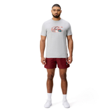A man faces forward wearing a Canterbury Uglies Logo T-shirt by Canterbury, featuring a UK flag graphic, paired with maroon shorts, white socks, and white athletic shoes on a plain white background.