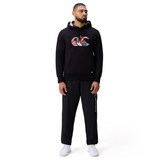 A man stands against a plain white background wearing the Canterbury Uglies Logo Hoodie in black by Canterbury, paired with black sweatpants and white sneakers.