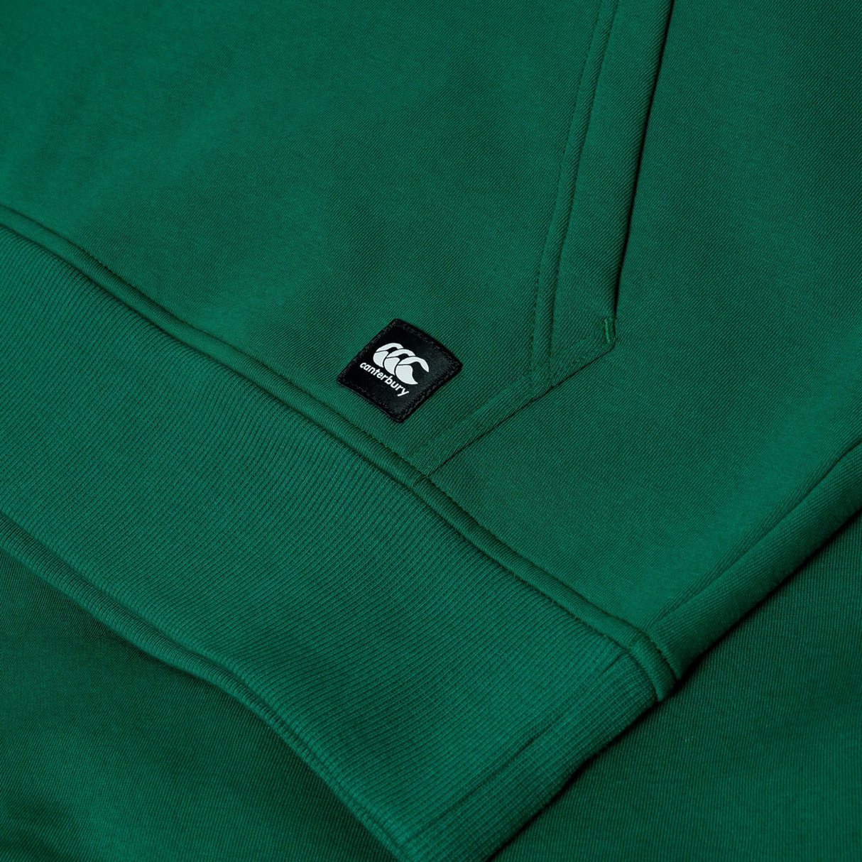 Close-up of the Canterbury Uglies Logo Hoodie in green, featuring ribbed cuffs and a small black and white Canterbury logo tag.