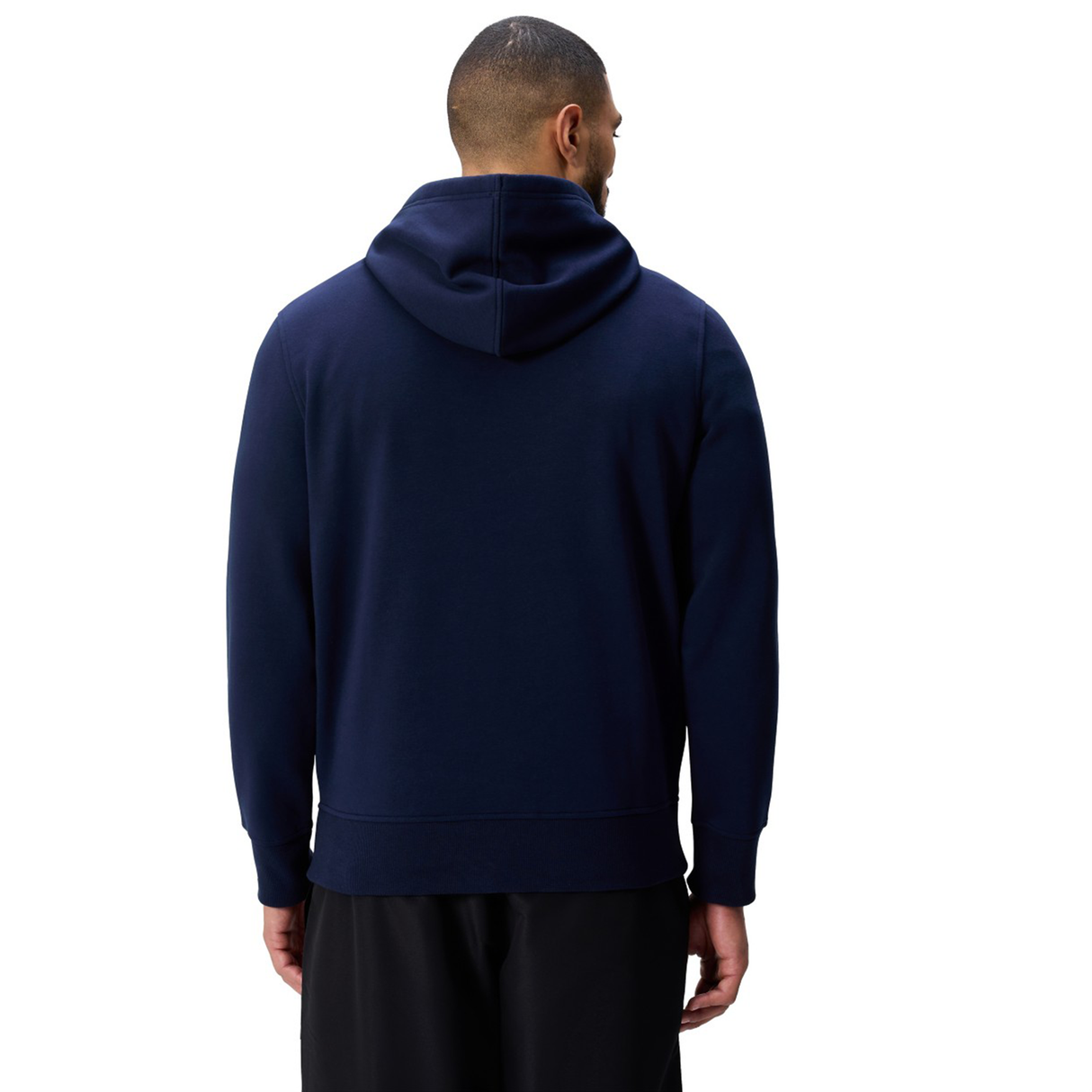 A person in a navy blue Canterbury Uglies Logo Hoodie and black pants stands with their back to the camera against a white background.