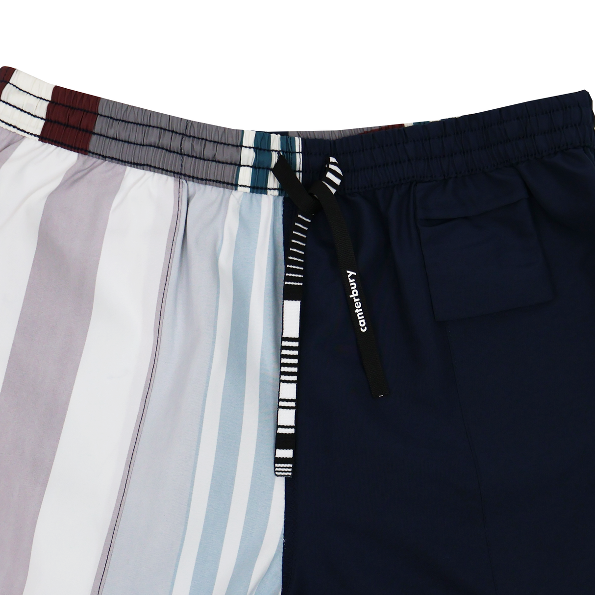 The Canterbury Uglies Harletic Short by Canterbury features vertical multicolored stripes on one side, solid navy on the other, a drawstring waistband, and a small pocket—ideal for classic rugby style.