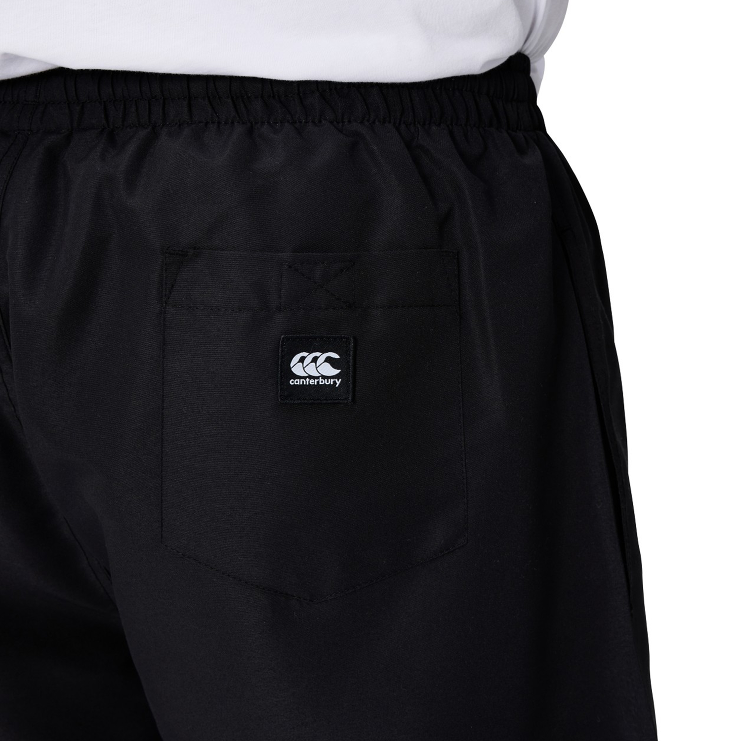 Close-up of a person wearing black Canterbury Uglies 5" Tactic Shorts featuring an elastic waistband, back pocket, and the Canterbury logo.