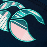 Close-up of a fabric patch with teal, white, and pink abstract shapes and stitching on dark blue, inspired by the bold patterns of Canterbury's Women's Uglies Tactic Short.