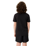A child with curly hair stands facing away from the camera, dressed in a black Canterbury Youth Uglies Logo T-shirt made from comfortable cotton and matching black shorts, with a subtle Canterbury logo visible against a plain white background.