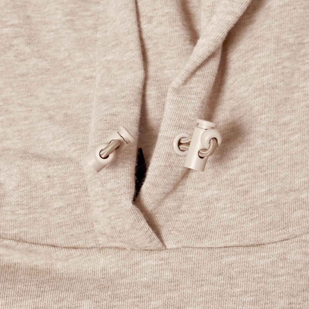 Close-up of Canterbury FORCE HOODIE in beige, highlighting the athletic fabric and two adjustable drawstrings with plastic toggles near the neckline.