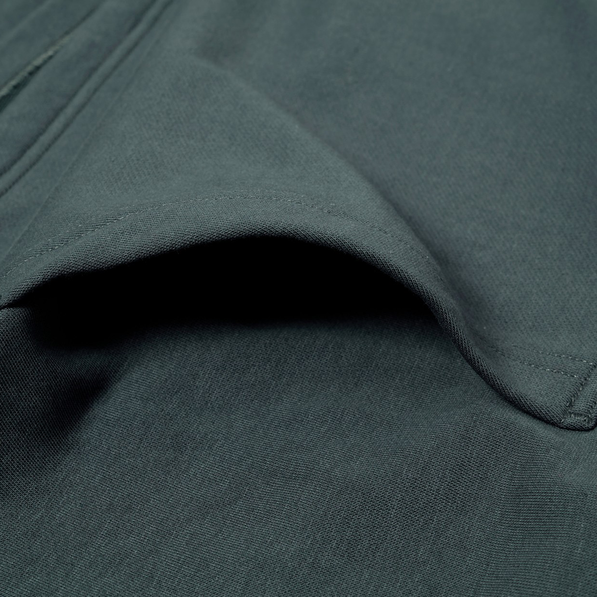 Close-up of Canterbury's FORCE HOODIE in dark green, highlighting the side pocket and visible seam stitching.