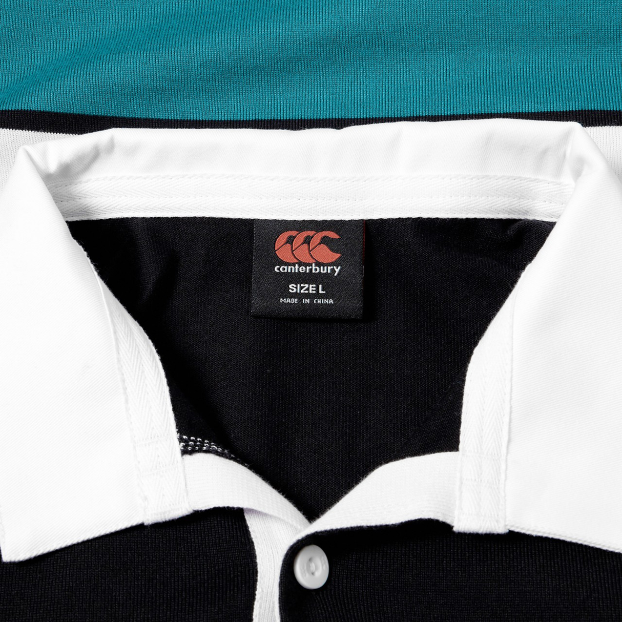Close-up of the Canterbury Uglies Short Sleeve Classic Rugby Jersey by Canterbury, showing its white collar, black body, and size L label—crafted from heavyweight cotton for durable comfort.