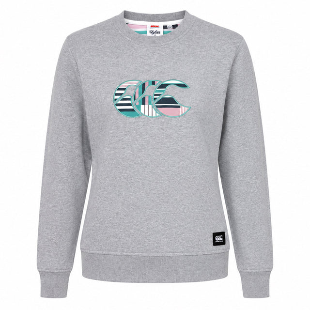 The Canterbury Women's Uglies Logo Crew Sweatshirt features a light grey crewneck design with a vibrant multicolored striped "CCC" logo on the chest, taking inspiration from the iconic Canterbury Uglies sweatshirt. Finished with a small black logo patch on the lower left hem, this must-have women's rugby sweatshirt by Canterbury blends laidback style and athletic heritage.