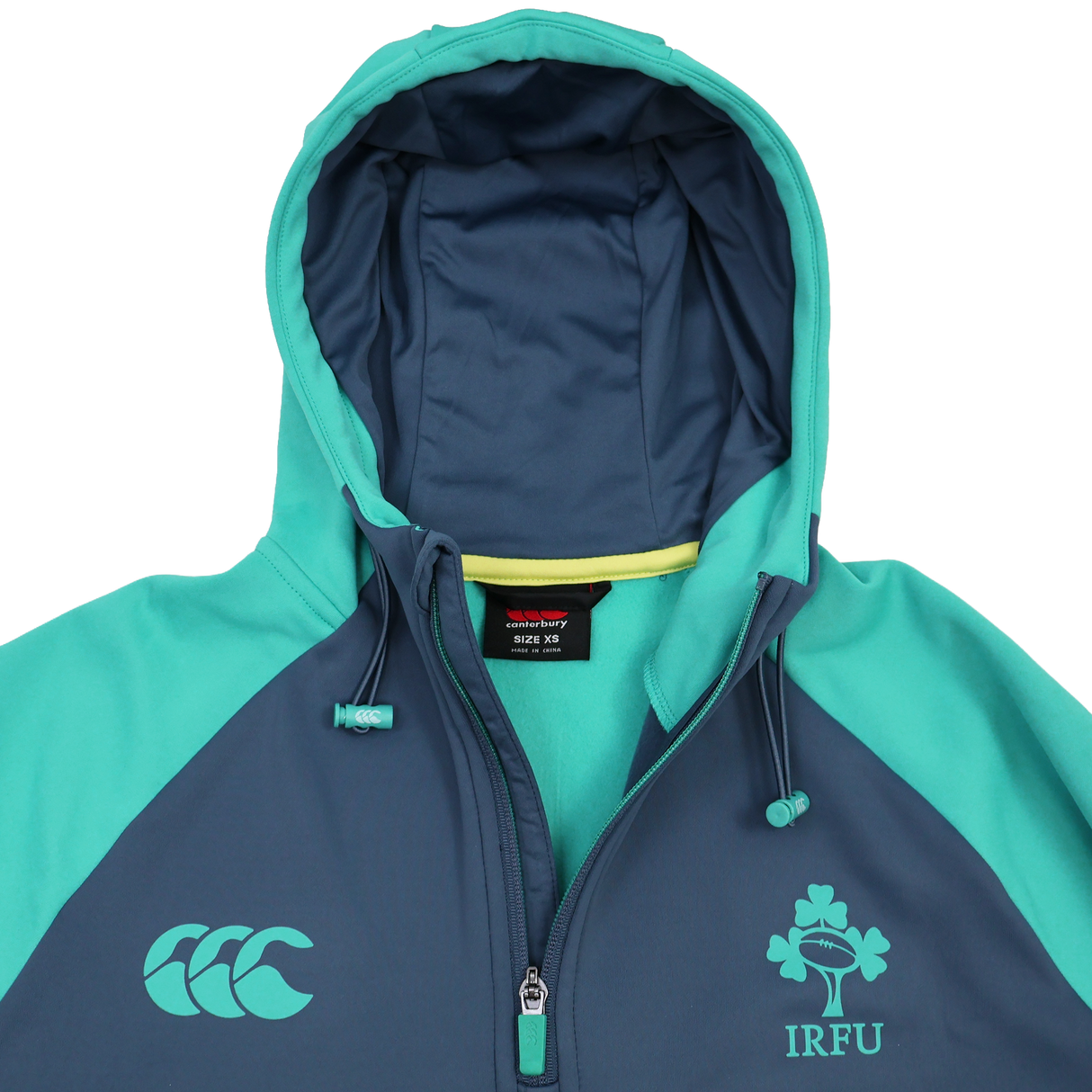 The Ireland 26/27 Summer Tour Training Hoodie by Canterbury features IRFU shamrock and CCC logos, a teal and navy design, flat lay with hood up and partial zip—ideal as a moisture-wicking training hoodie for the Ireland Summer Tour.