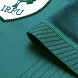 Close-up of a green jersey sleeve with thin stripes and the IRFU logo patch in the top left corner, highlighting the distinctive design of the Canterbury Ireland 26 Home Test Jersey.