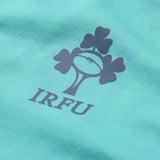 Close-up of the IRFU logo, showcasing a rugby ball and shamrock printed on teal fabric, from the Ireland 26 1/4 Zip Training Top by Canterbury, featuring advanced Thermoreg technology.