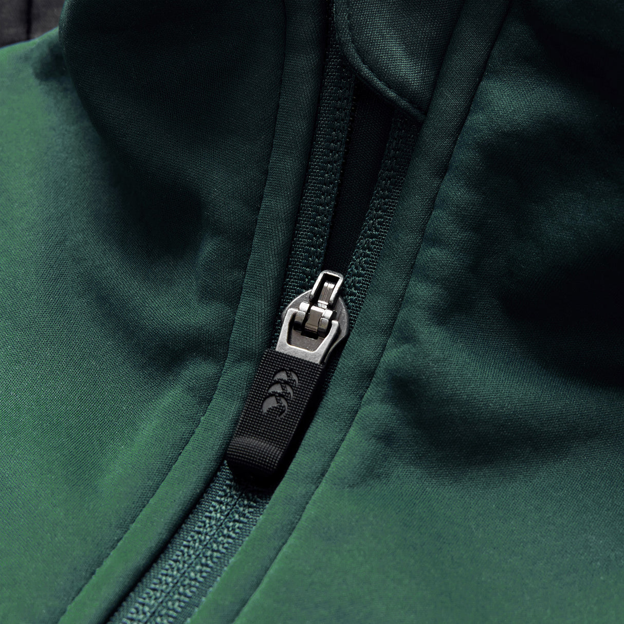 Close-up of the Ireland 26 1/4 Zip Training Top by Canterbury, showcasing a dark green design with a partially zipped silver zipper and a black fabric pull tab, styled in Canterbury’s signature 1/4 zip fashion.