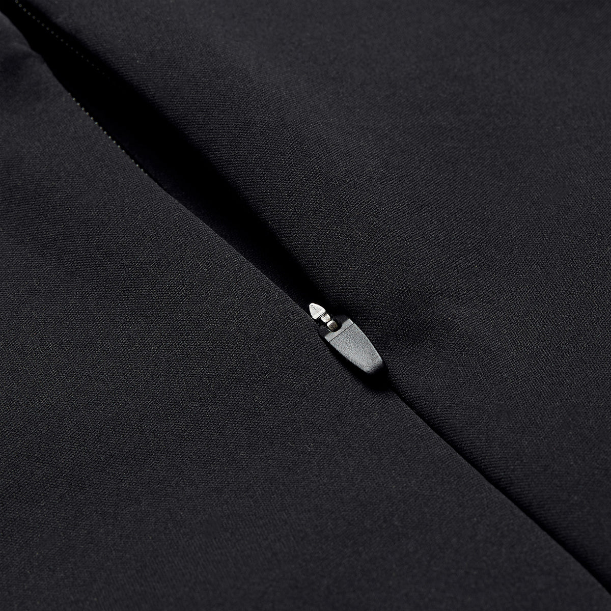 Close-up of a partially unzipped black fabric zipper on the Ireland 26 1/4 Zip Training Top by Canterbury, highlighting the metal zipper pull and textured material, enhanced with Thermoreg technology.