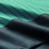 Close-up of two fabrics: one green with thin black stripes, inspired by the Canterbury Ireland 26/27 Summer Tour Superlight Training Tank, and one textured dark blue. The fabrics overlap diagonally.