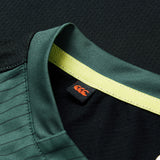 Close-up of the Ireland 26 Training Tank by Canterbury AW26 sports jersey collar in green, featuring a yellow stripe and a black tag with an orange Canterbury logo.