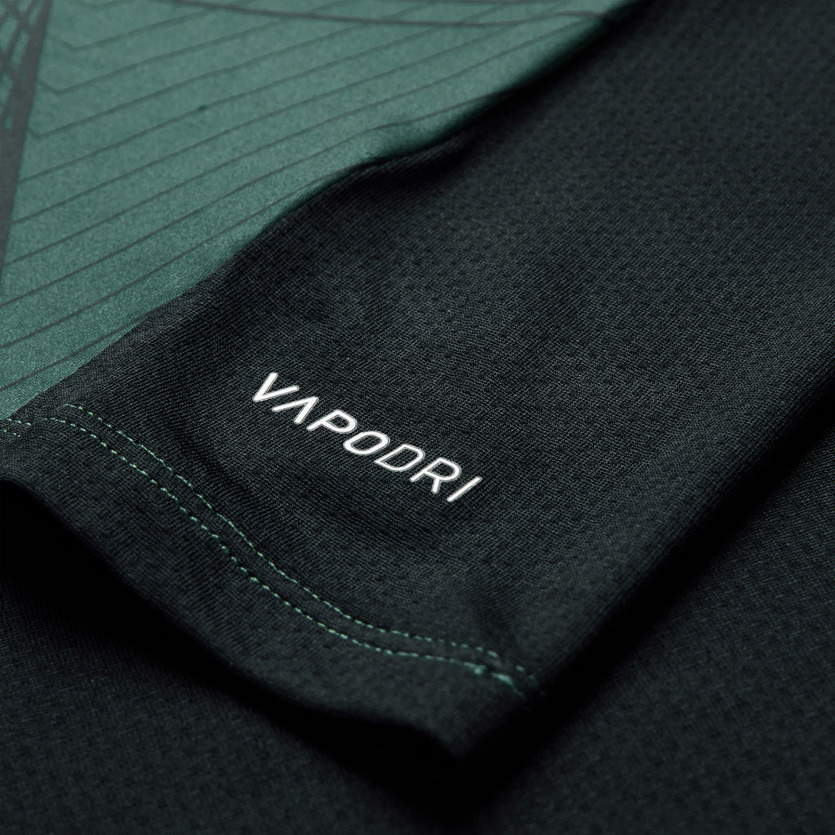 Close-up of a black athletic shirt sleeve from the Canterbury Ireland 26 Training Tank, featuring “VAPODRI” printed in white and a subtle green geometric pattern inspired by the latest Canterbury design.