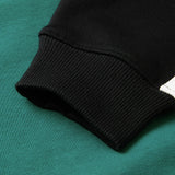 Close-up of the sleeve of the Women’s Ireland 26 Legends 1/4 Zip Sweatshirt by Canterbury resting on a green fabric surface, highlighting the texture and stitching details of the materials.