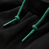Close-up of a black hoodie with green drawstrings, highlighting the intricate knot detail and plastic aglets at each end, styled effortlessly with the Canterbury Women’s Ireland 26 Legends Fleece Pant for a sporty yet comfortable outfit.