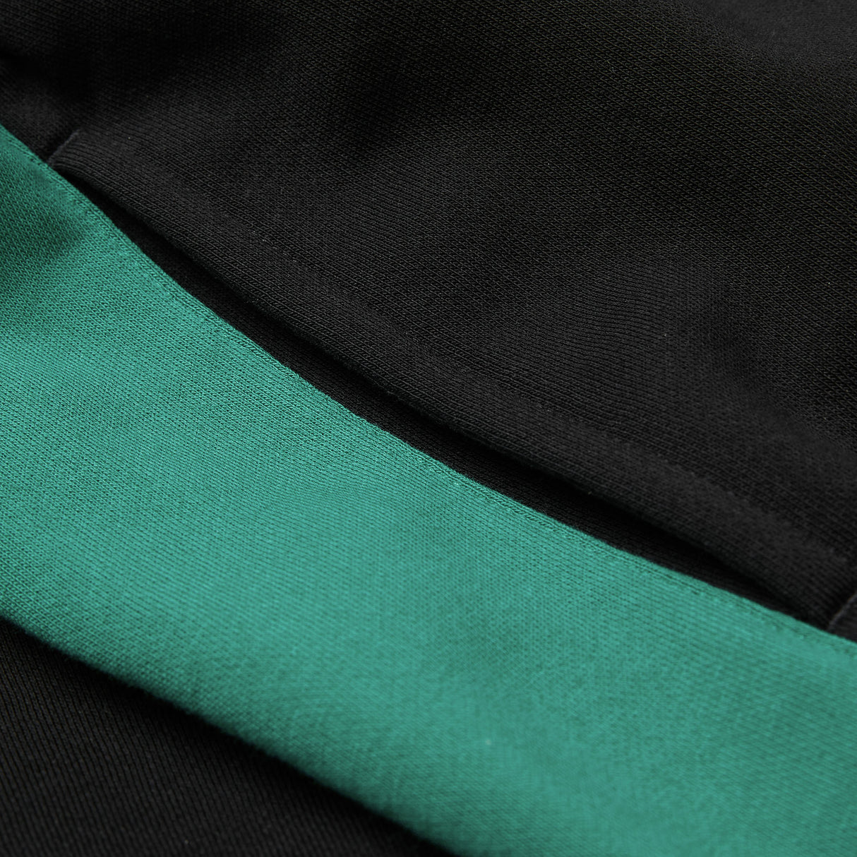 Close-up of black fabric from the Women’s Ireland 26 Legends Fleece Pant by Canterbury, with a green band or stripe running diagonally across the image.
