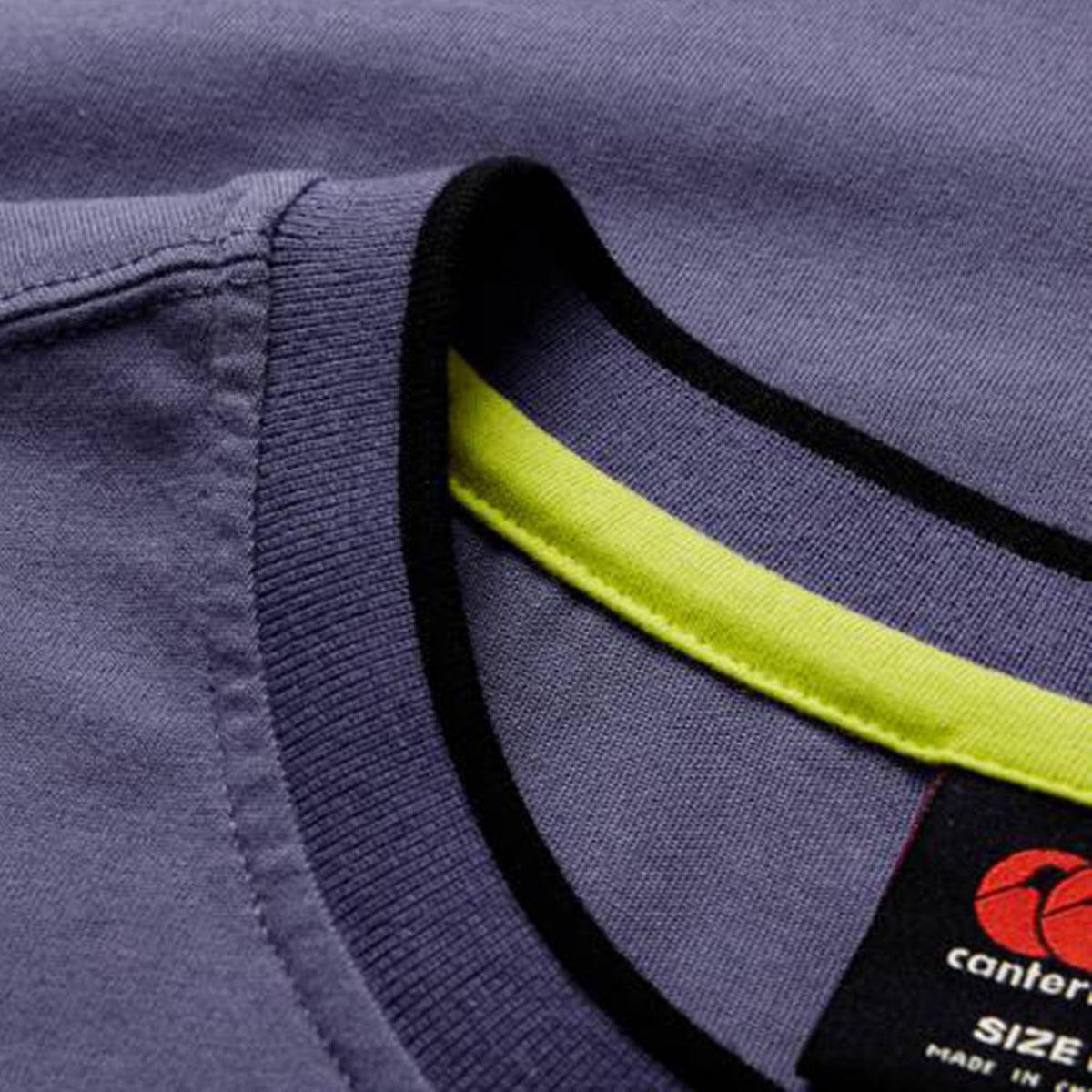 Close-up of the Women’s Ireland 26 Cotton T-shirt by Canterbury in purple, featuring a black Canterbury label inside the collar and a visible yellow accent along the inner neckline.