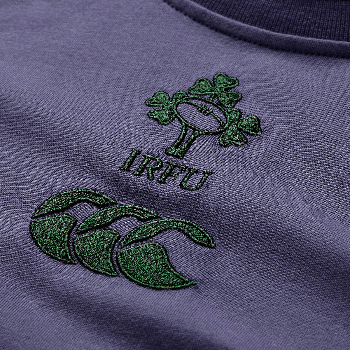 Close-up of the Women’s Ireland 26 Cotton T-shirt by Canterbury in purple, featuring the embroidered IRFU shamrock rugby logo with the green Canterbury logo below it.
