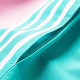 Close-up of the turquoise Canterbury Uglies Harletic Short fabric, featuring white diagonal stripes and a visible seam, set against a pink background.