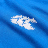 Close-up of the white Canterbury logo with three overlapping stylized “C”s printed on vibrant blue fabric, highlighting the quality and style of the lightweight Canterbury Tempo+ GFX Training T-Shirt.